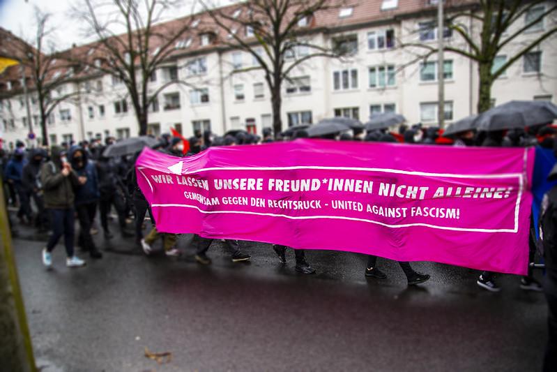 Foto von der Solidemo am 20.02.22 in Braunschweig. Pinkes Transparent mit der Aufschrift "Wir lassen unsere Freund*innen nicht alleine! Gemeinsam gegen den Rechtsruck - United against fascism"